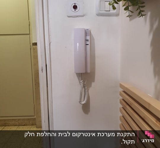 אינטרקום לבן תלוי על קיר עם כבל טלפון